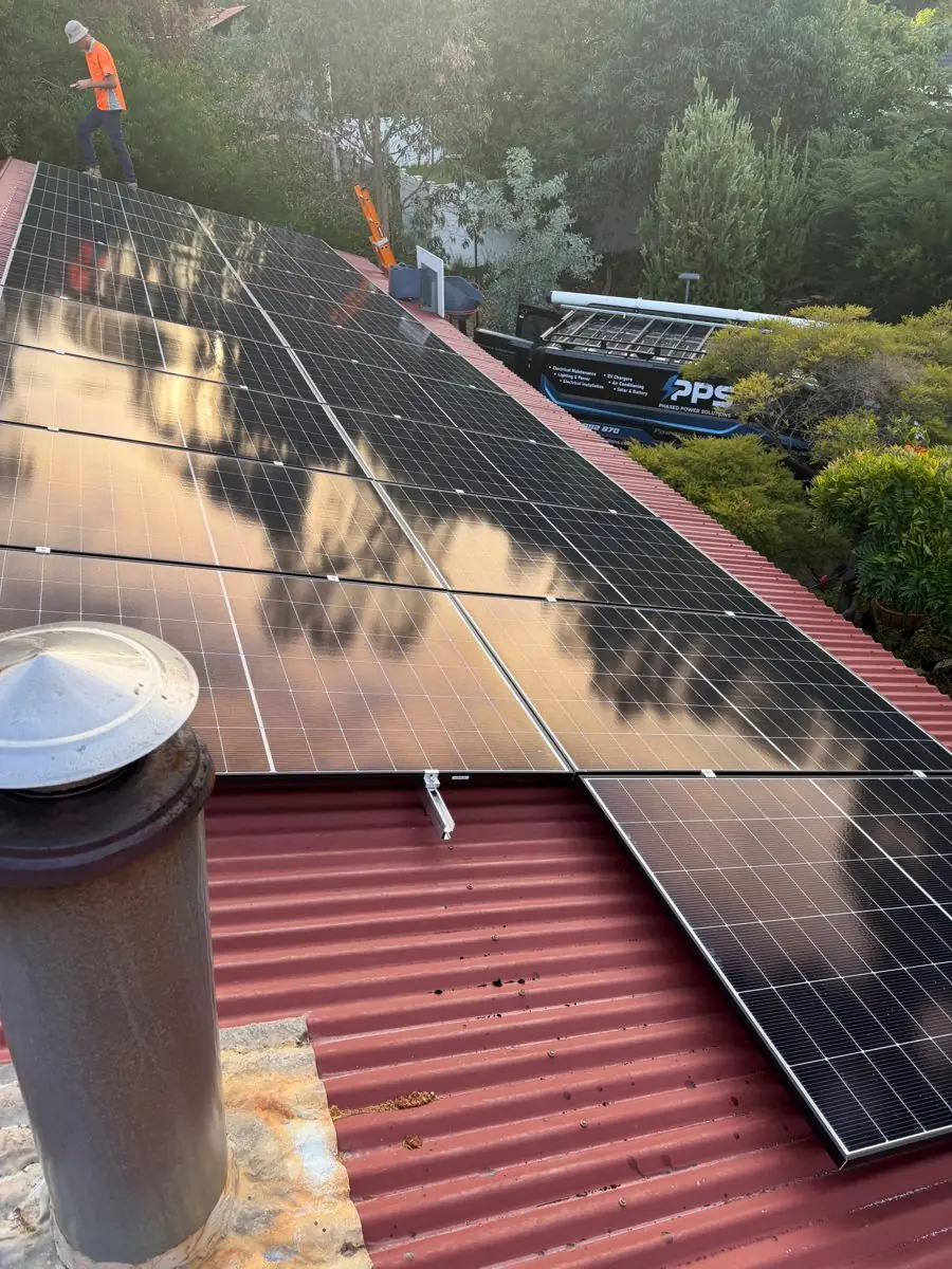 Solar panels on a red corrugated roof with PPS van below