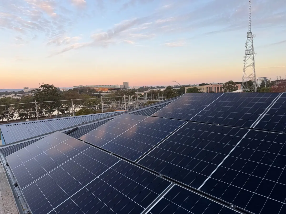 Commercial rooftop solar array with Optus Stadium and the Perth skyline behind